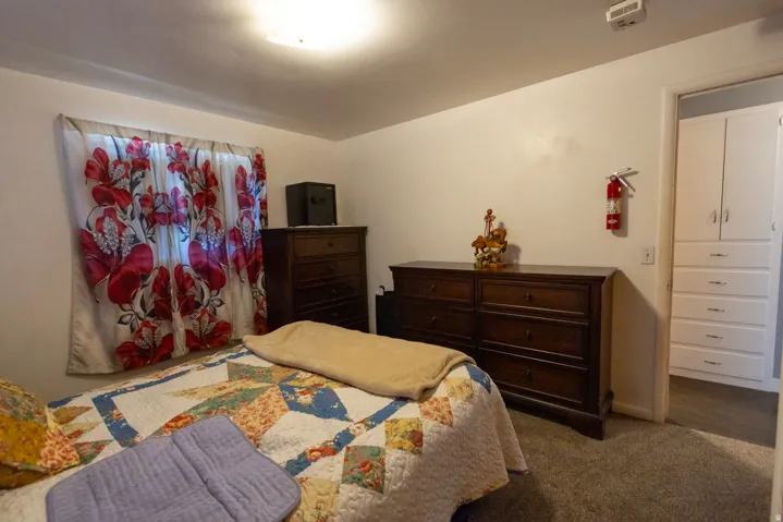 Carpeted bedroom with a window featuring decorative drapes