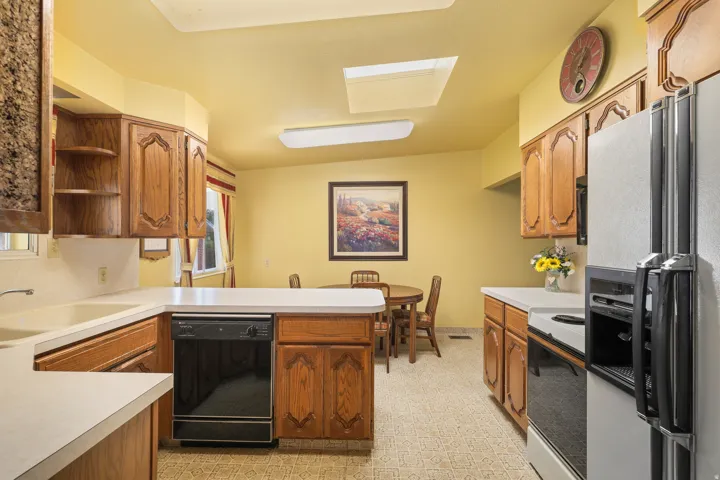 Kitchen featuring wood cabinetry, white countertops, a double basin sink, and a skylight