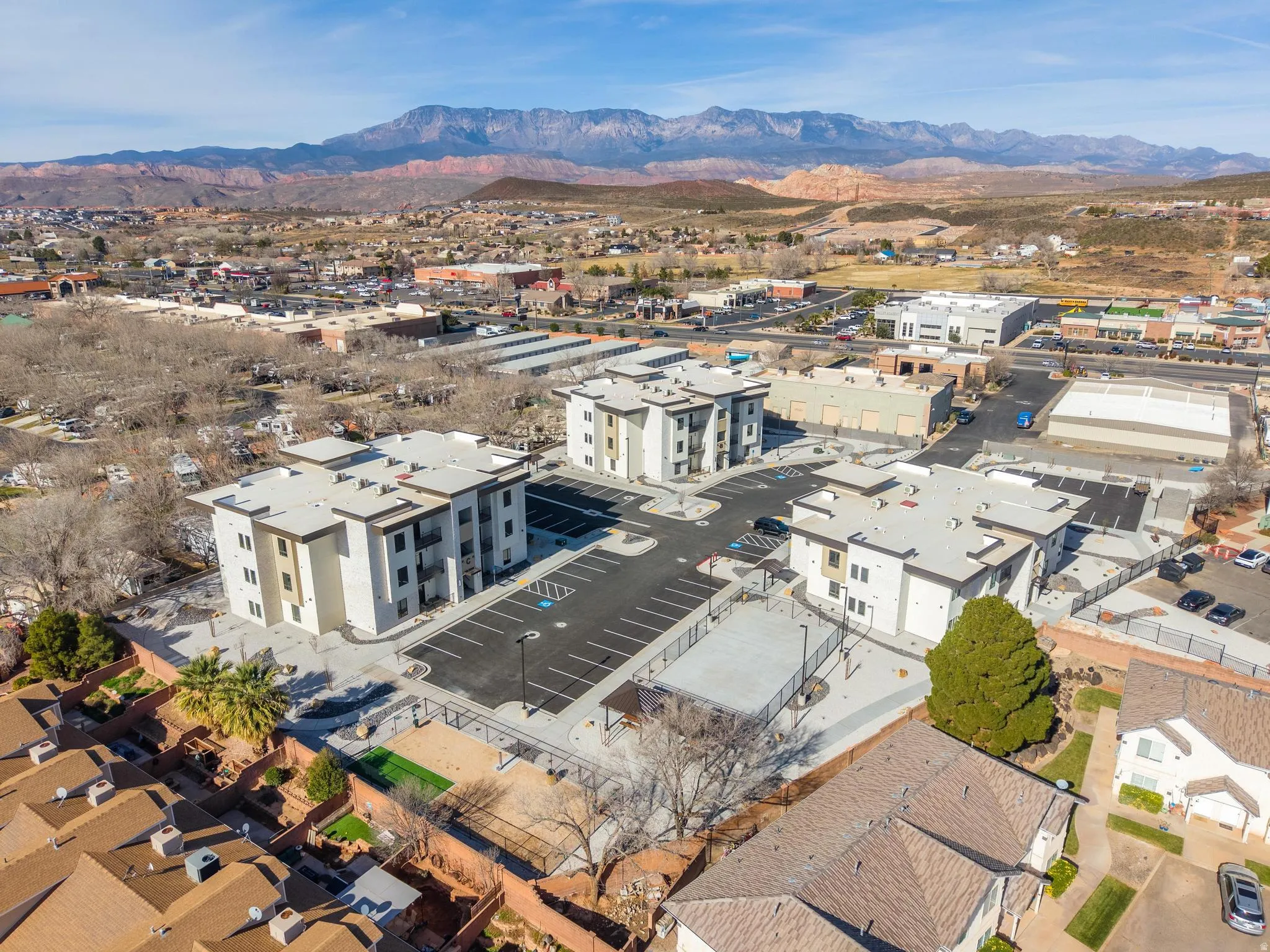 Modern apartment complex featuring multiple buildings with contemporary exterior finishes, ample paved parking, and a dedicated recreational court