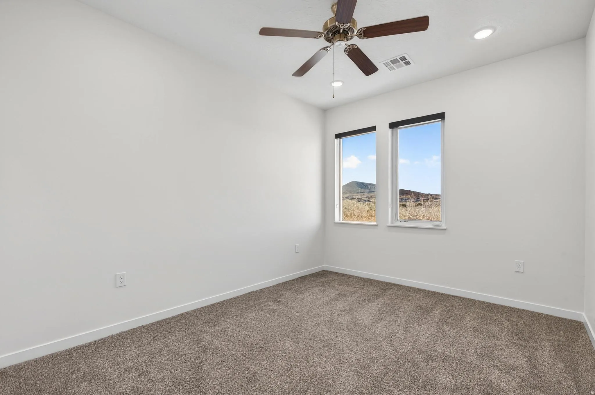 Room featuring textured carpet flooring, white walls, and a ceiling fan with integrated lighting
