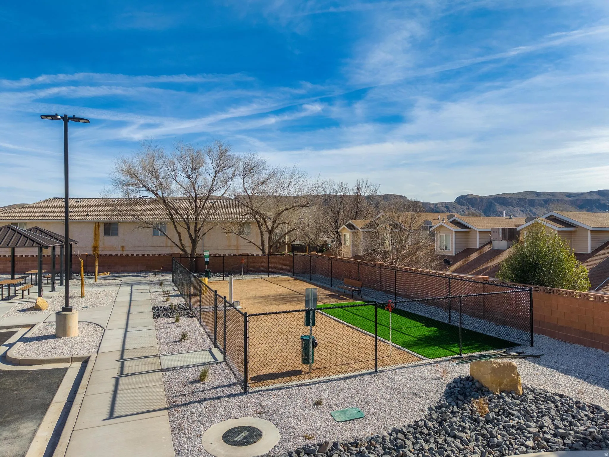 Dedicated pet recreation area featuring chain-link fencing, artificial turf, and a gravel-covered space