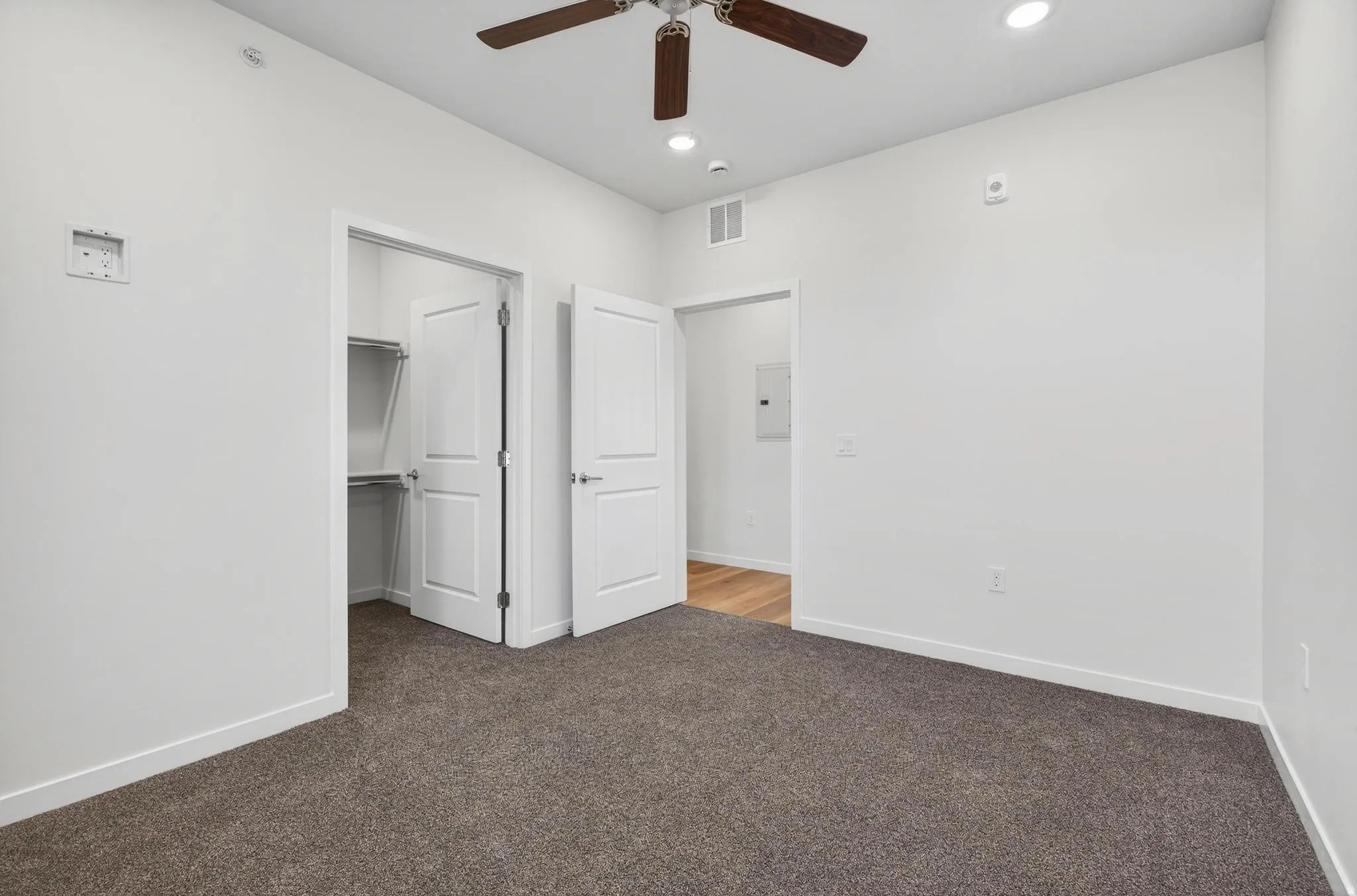 Neutral-toned carpeting in a room featuring a ceiling fan with light, recessed ceiling lighting, and a closet with bifold doors and shelving