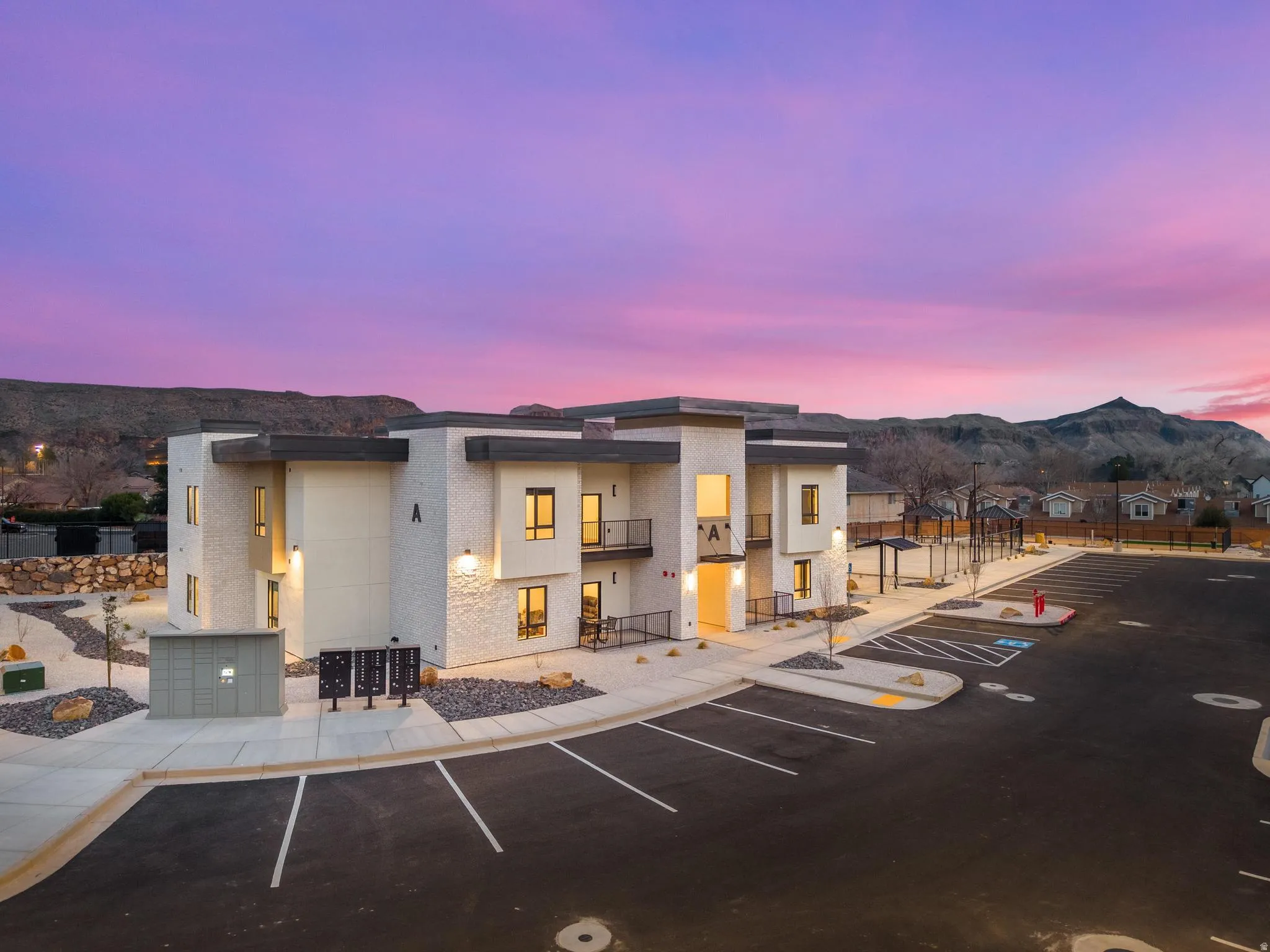 Modern multi-unit building with a white textured facade and dark trim accents