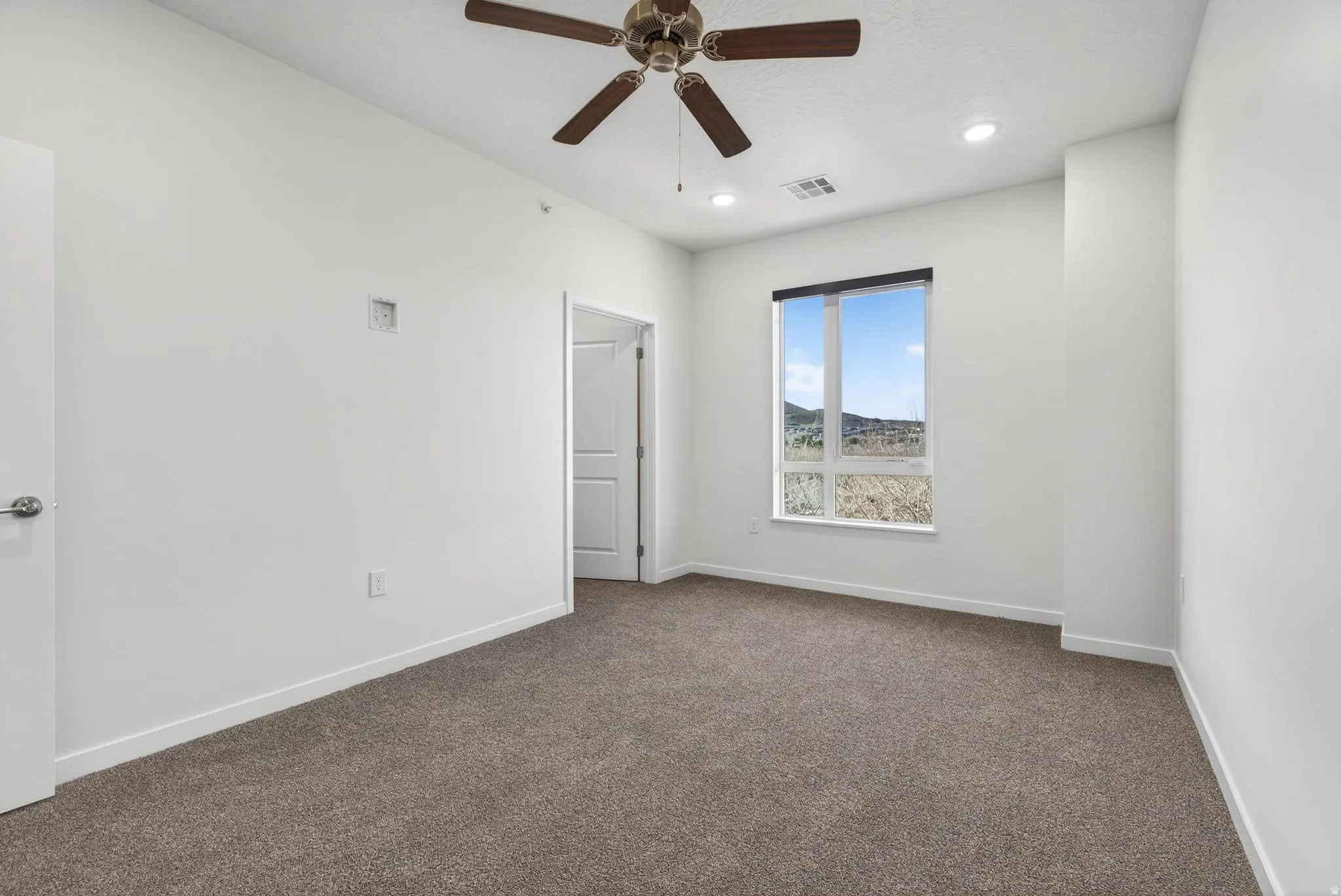 Carpeted room with a ceiling fan, recessed lighting, and a large window offering scenery
