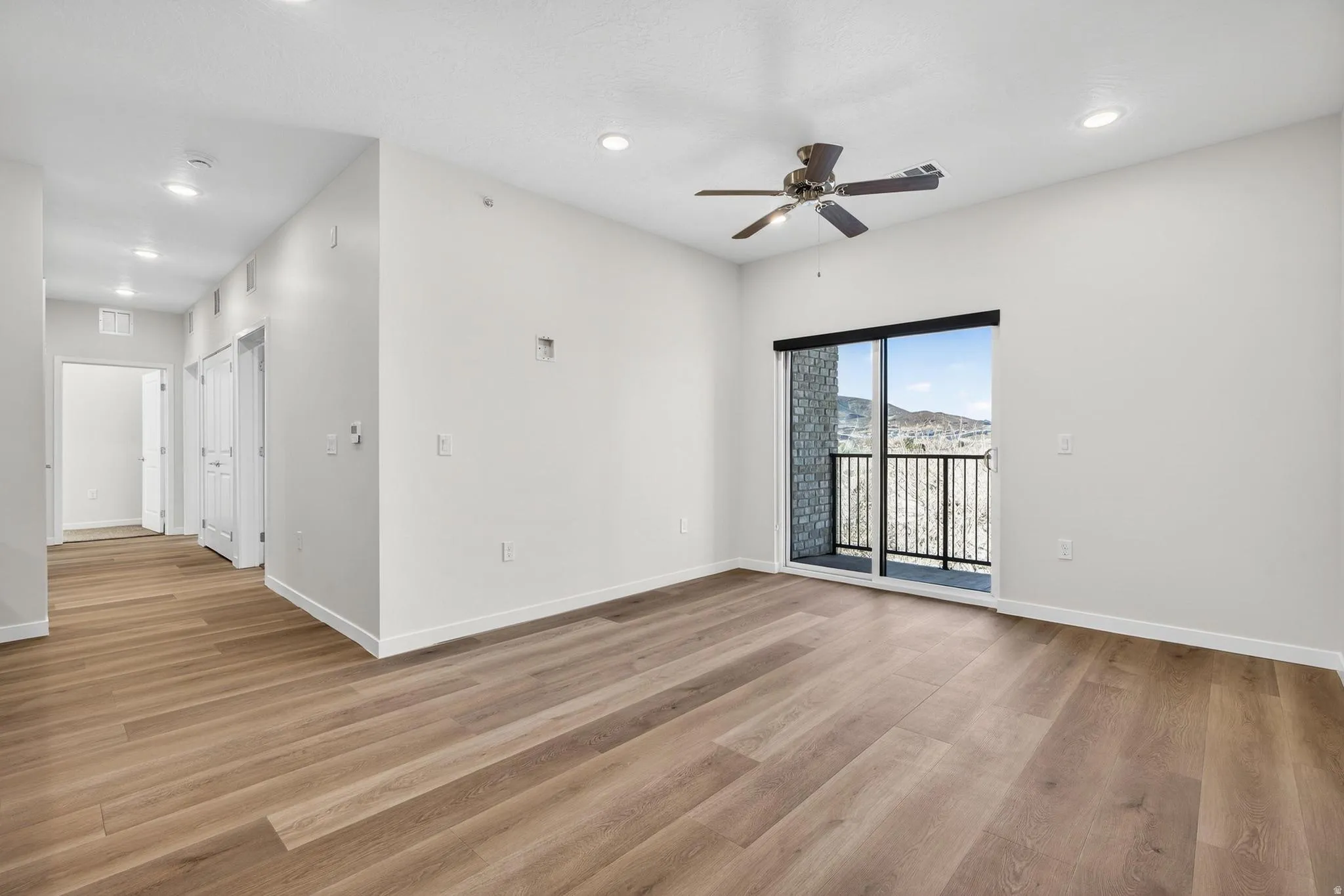 Spacious room featuring wood-finish flooring, recessed lighting, and a contemporary ceiling fan