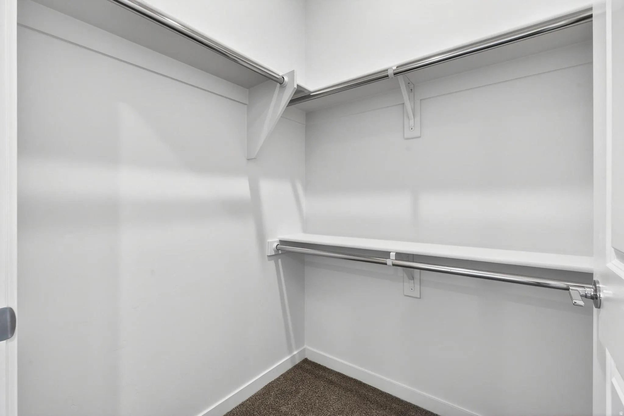 Walk-in closet featuring white painted walls, shelving, and chrome hanging rods