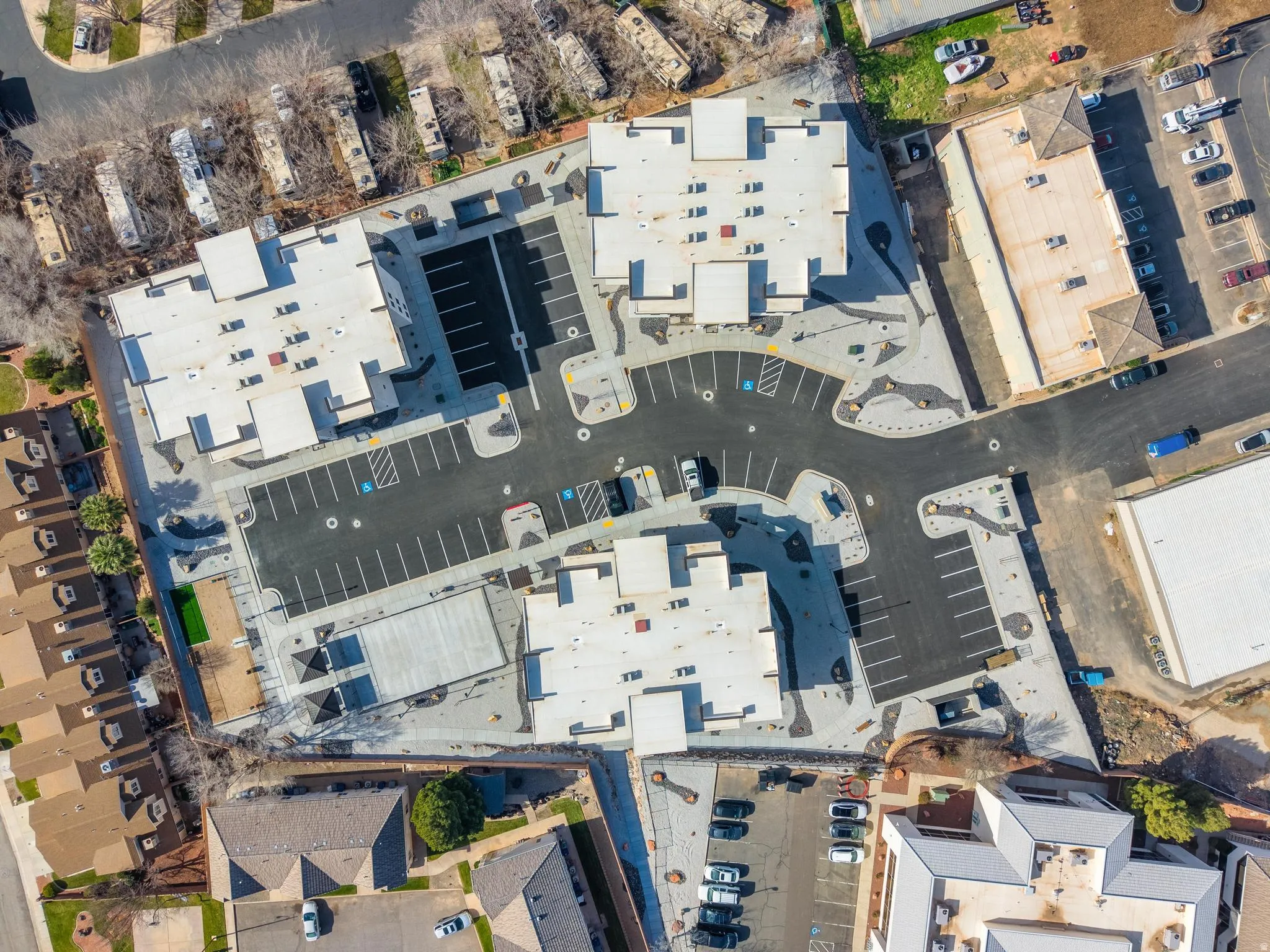 Newly constructed multi-building complex featuring extensive paved parking areas, accessible parking spaces, and varied architectural rooflines