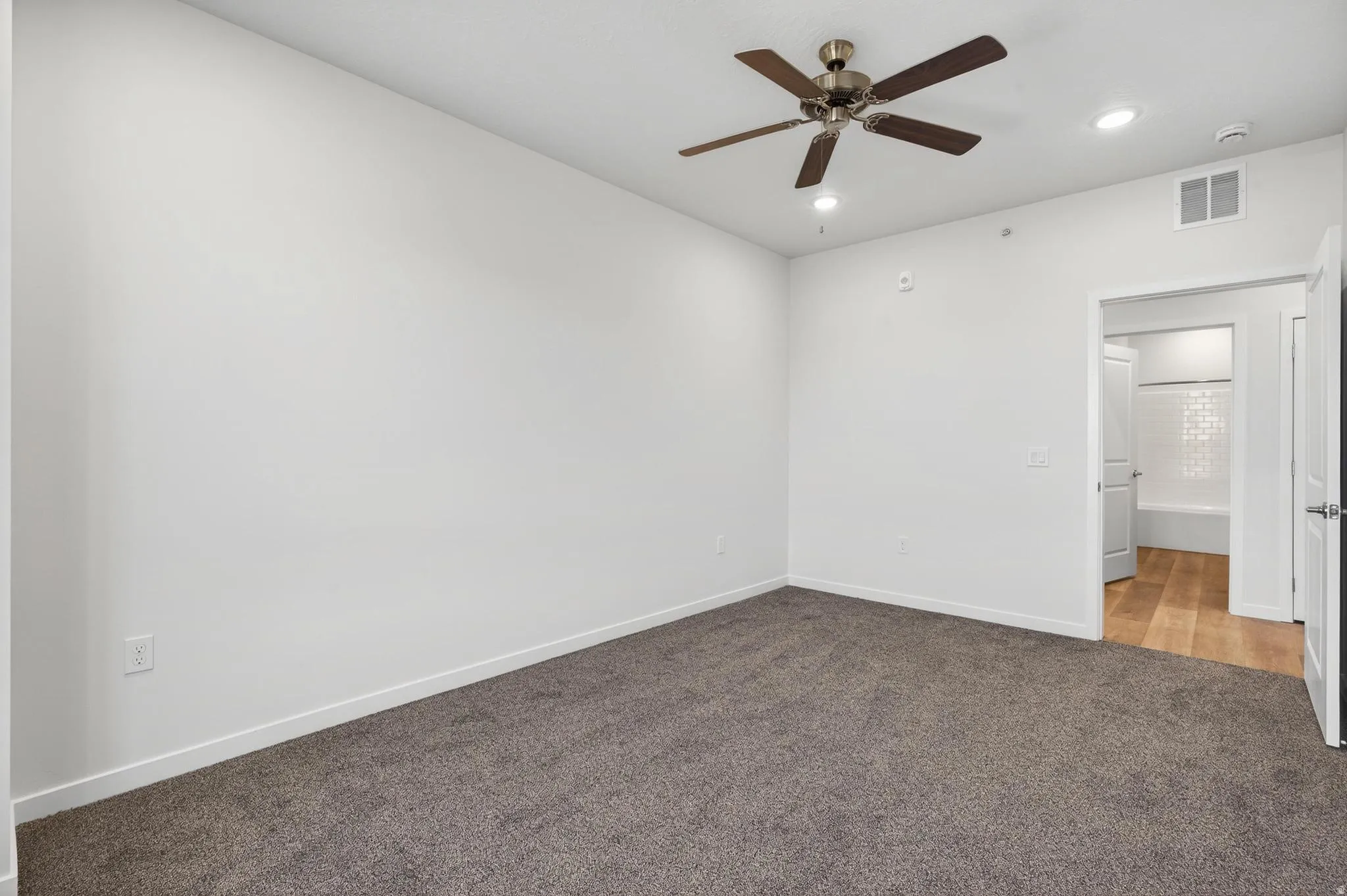 Spacious room featuring neutral carpeting, a ceiling fan with integrated lighting, and recessed lighting