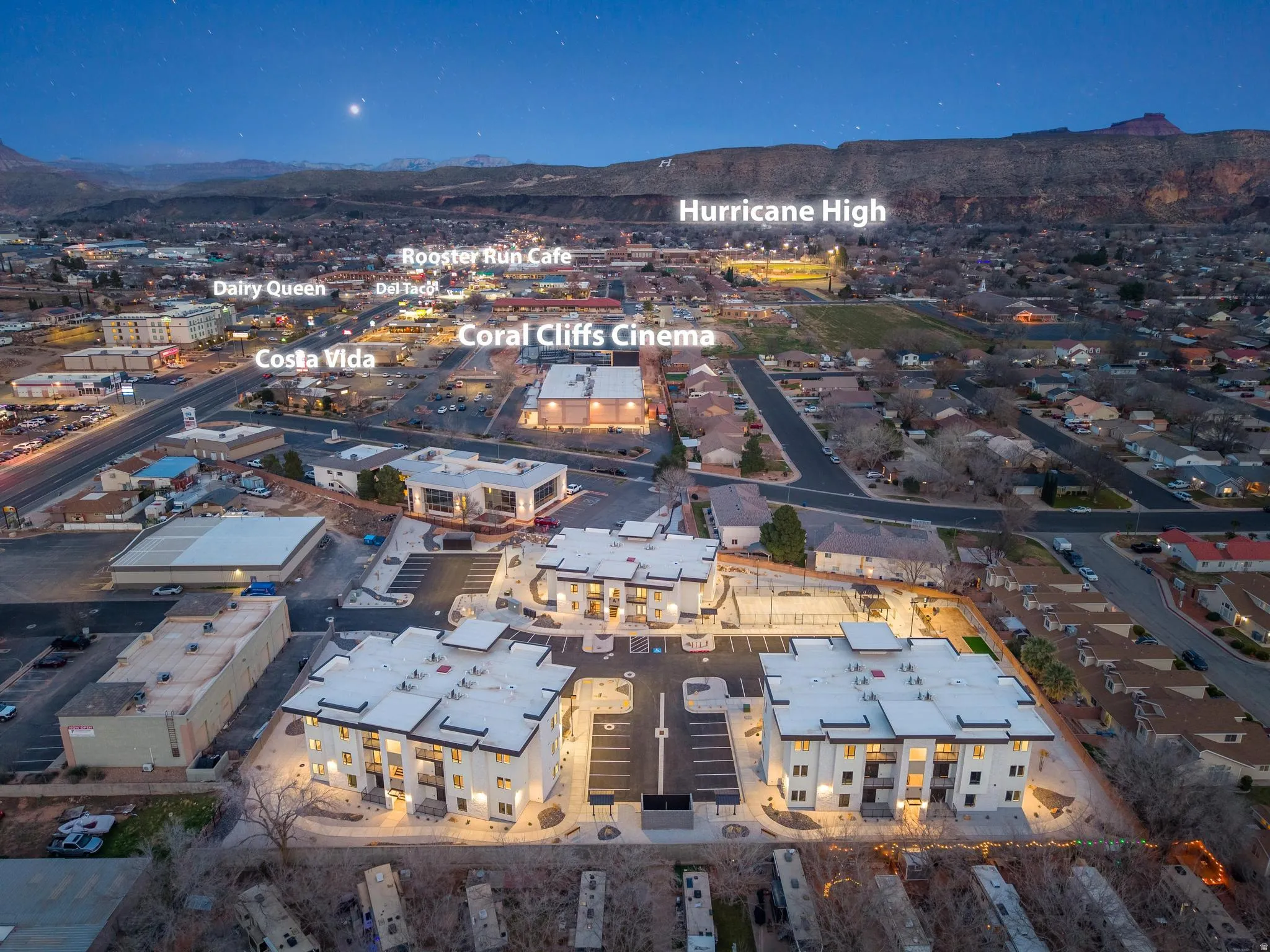 Contemporary multi-story buildings featuring illuminated exteriors and ample surface parking