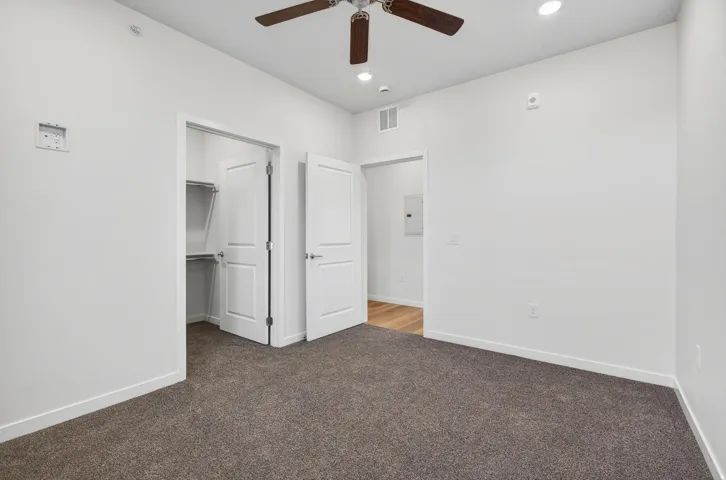 Neutral-toned carpeting in a room featuring a ceiling fan with light, recessed ceiling lighting, and a closet with bifold doors and shelving