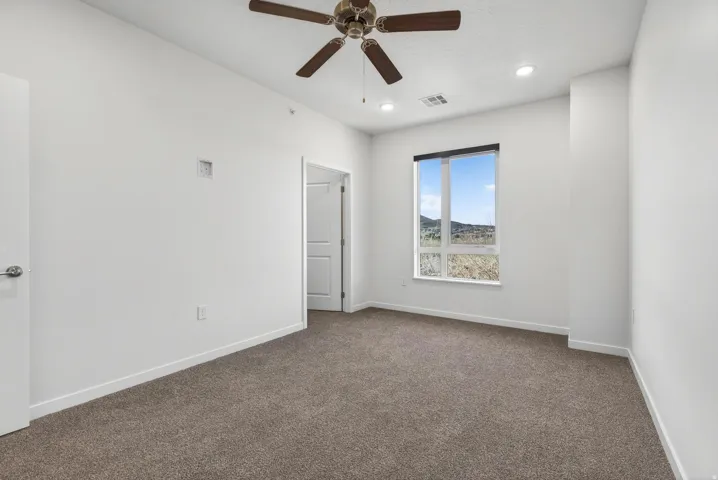 Carpeted room with a ceiling fan, recessed lighting, and a large window offering scenery