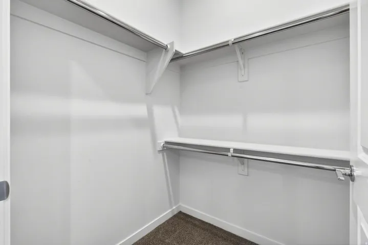 Walk-in closet featuring white painted walls, shelving, and chrome hanging rods