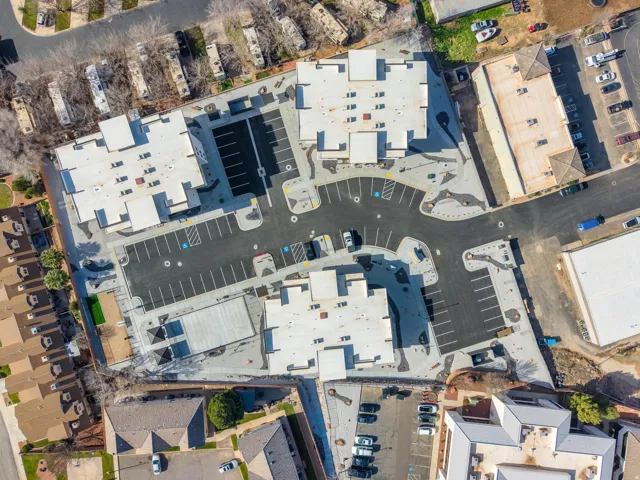 Newly constructed multi-building complex featuring extensive paved parking areas, accessible parking spaces, and varied architectural rooflines