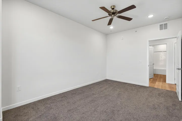 Spacious room featuring neutral carpeting, a ceiling fan with integrated lighting, and recessed lighting