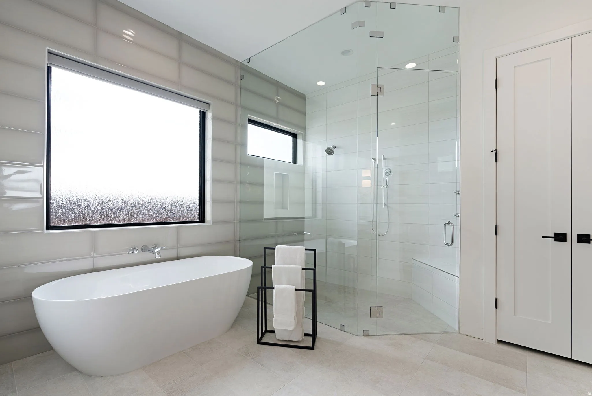Contemporary bathroom featuring a freestanding soaking tub, a spacious glass-enclosed shower with a built-in bench, and large format wall tiling
