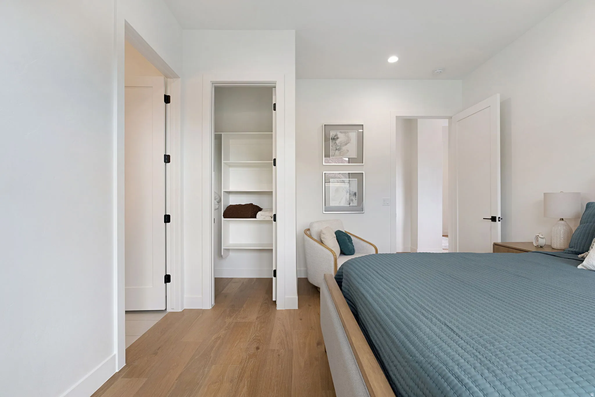 Bedroom featuring wood-finish flooring, recessed lighting, white walls, and a built-in closet with shelving