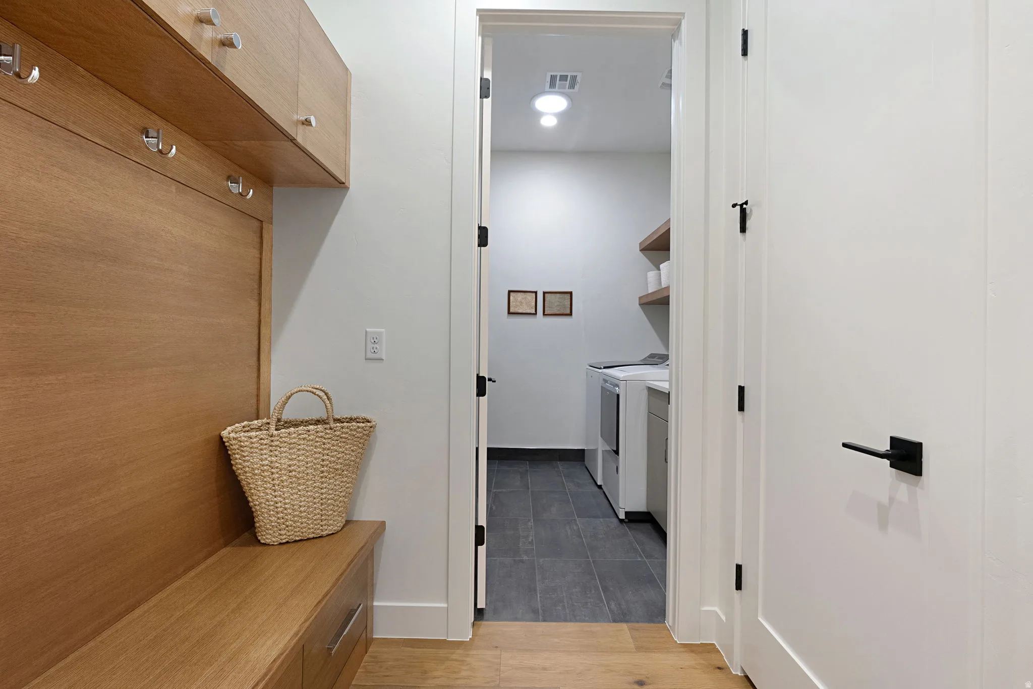 Built-in wood-finish bench with storage drawers and overhead cabinetry featuring coat hooks