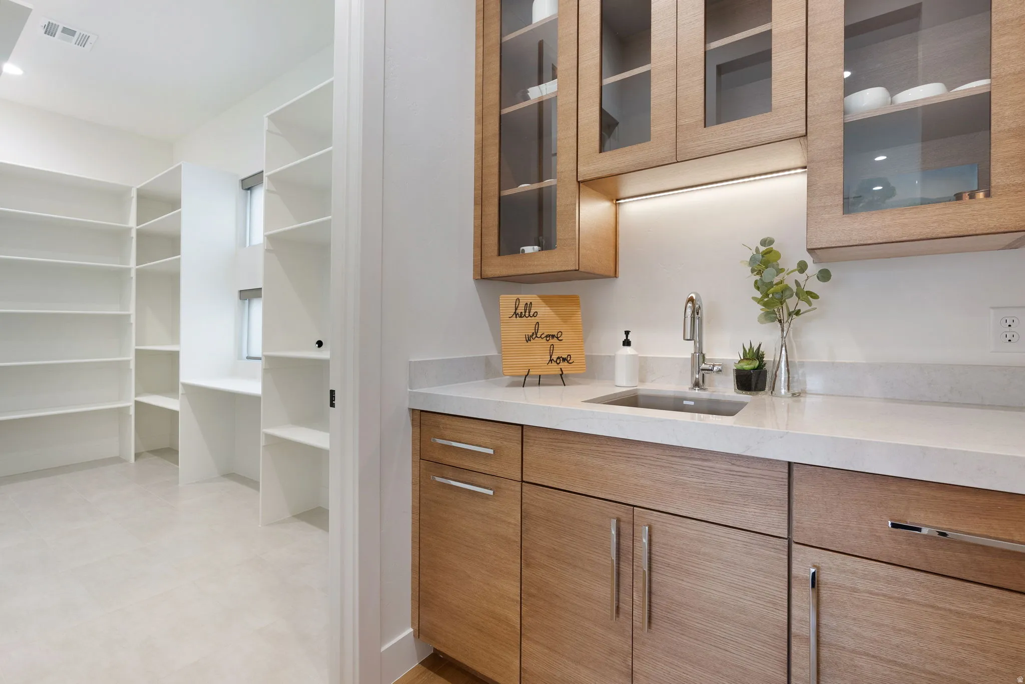 Light wood-finish cabinetry with glass upper doors and under-cabinet lighting