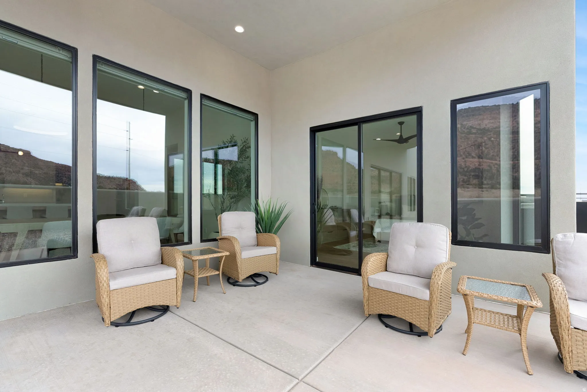 Expansive outdoor patio featuring a concrete surface, recessed lighting, and multiple tall windows with black frames