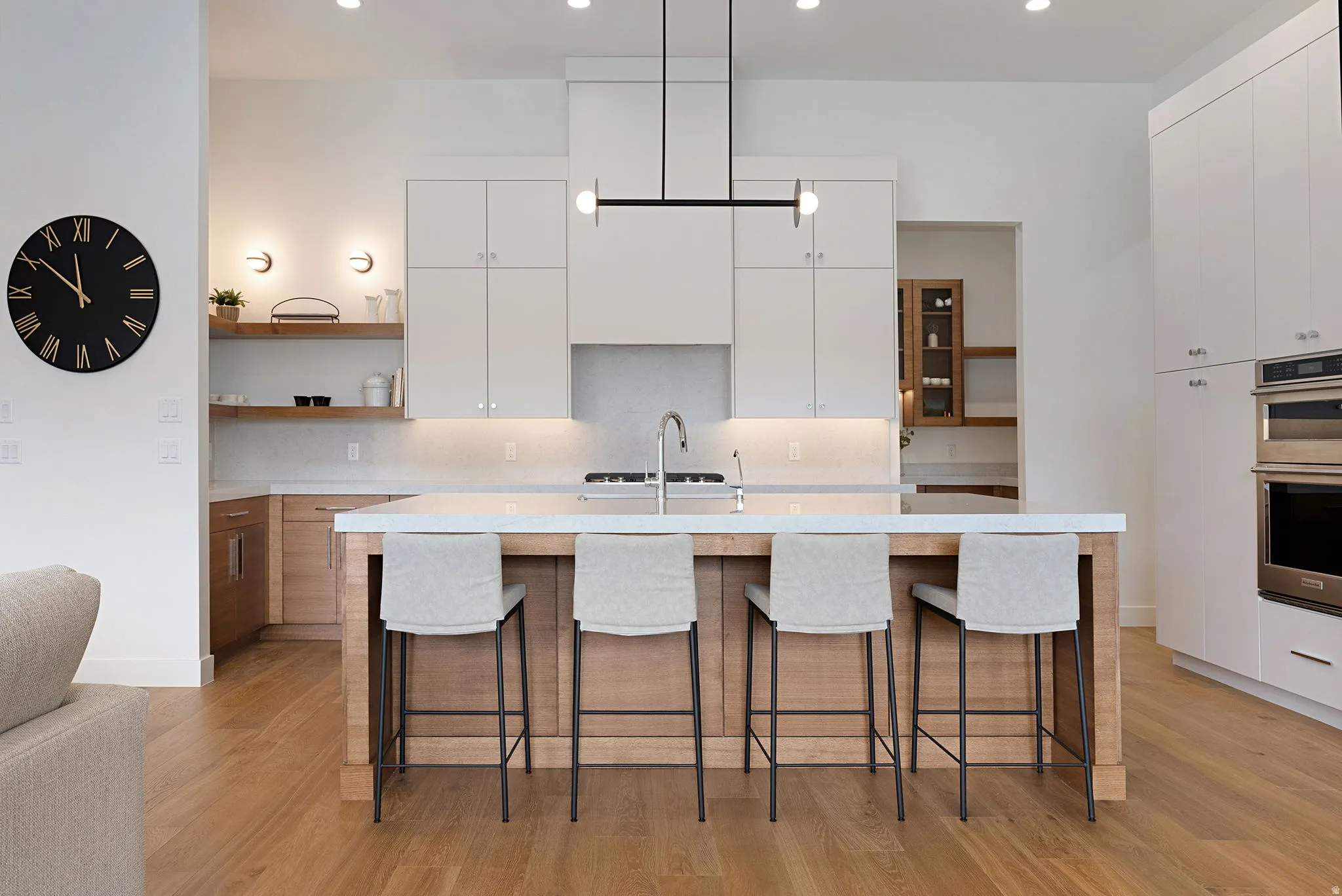 Gourmet kitchen featuring a substantial island with seating, a contemporary linear chandelier, built-in stainless steel appliances, and wood-finish flooring