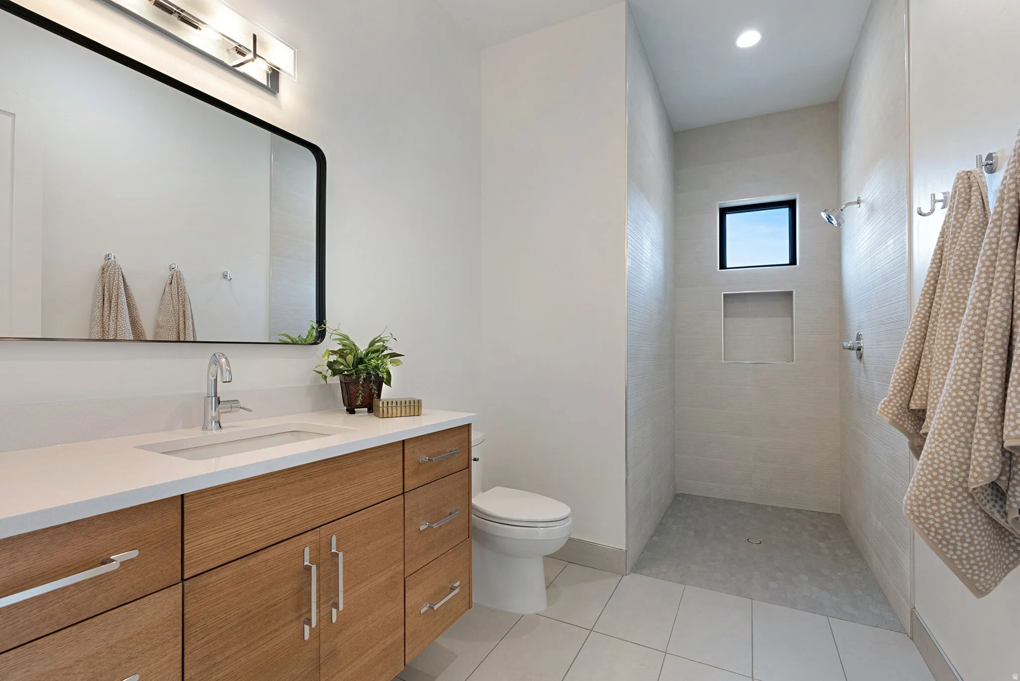 Modern bathroom featuring a wood-finish vanity with an integrated sink and chrome fixtures
