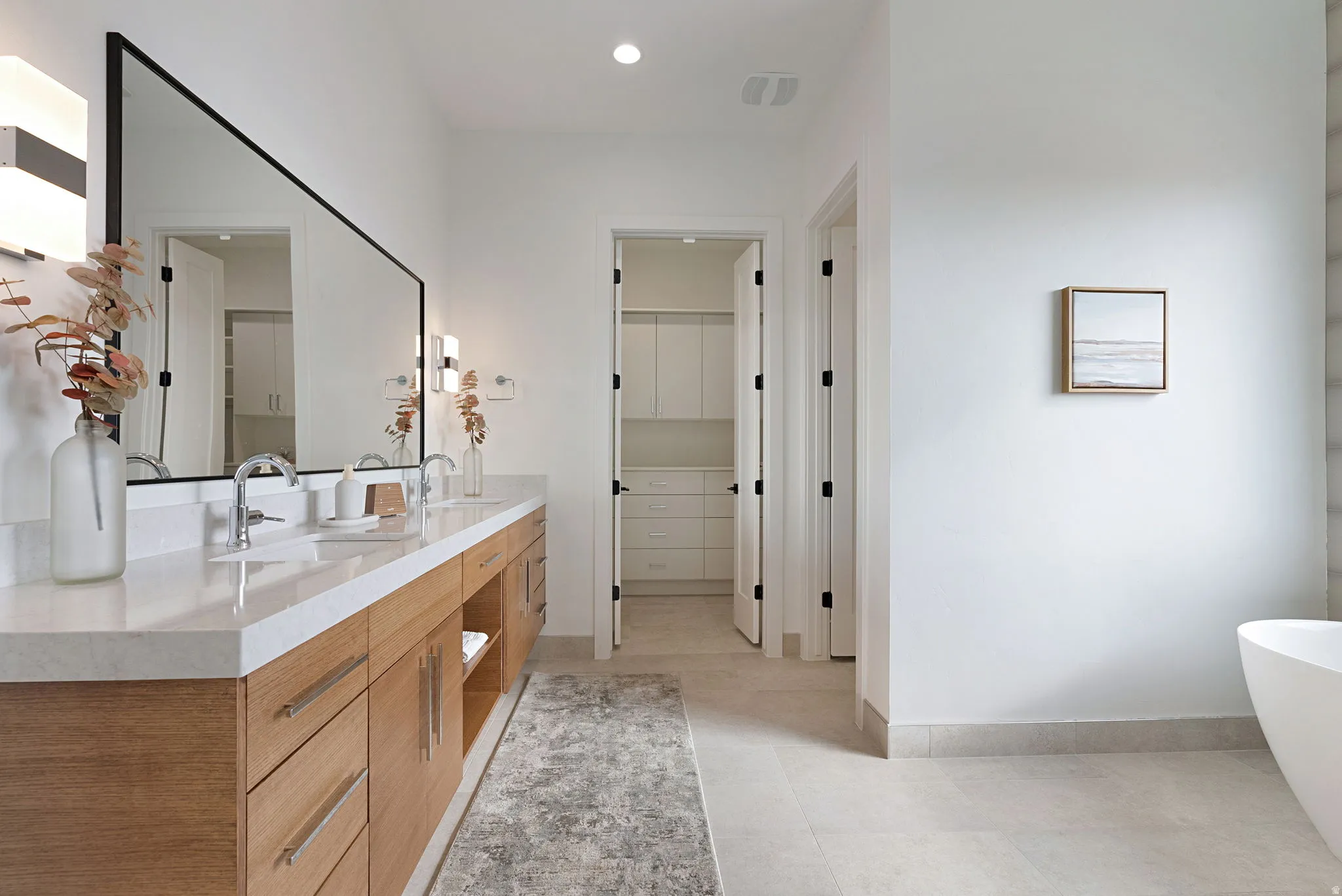 Dual vanity with a light-toned countertop, chrome fixtures, and natural wood-finish cabinetry