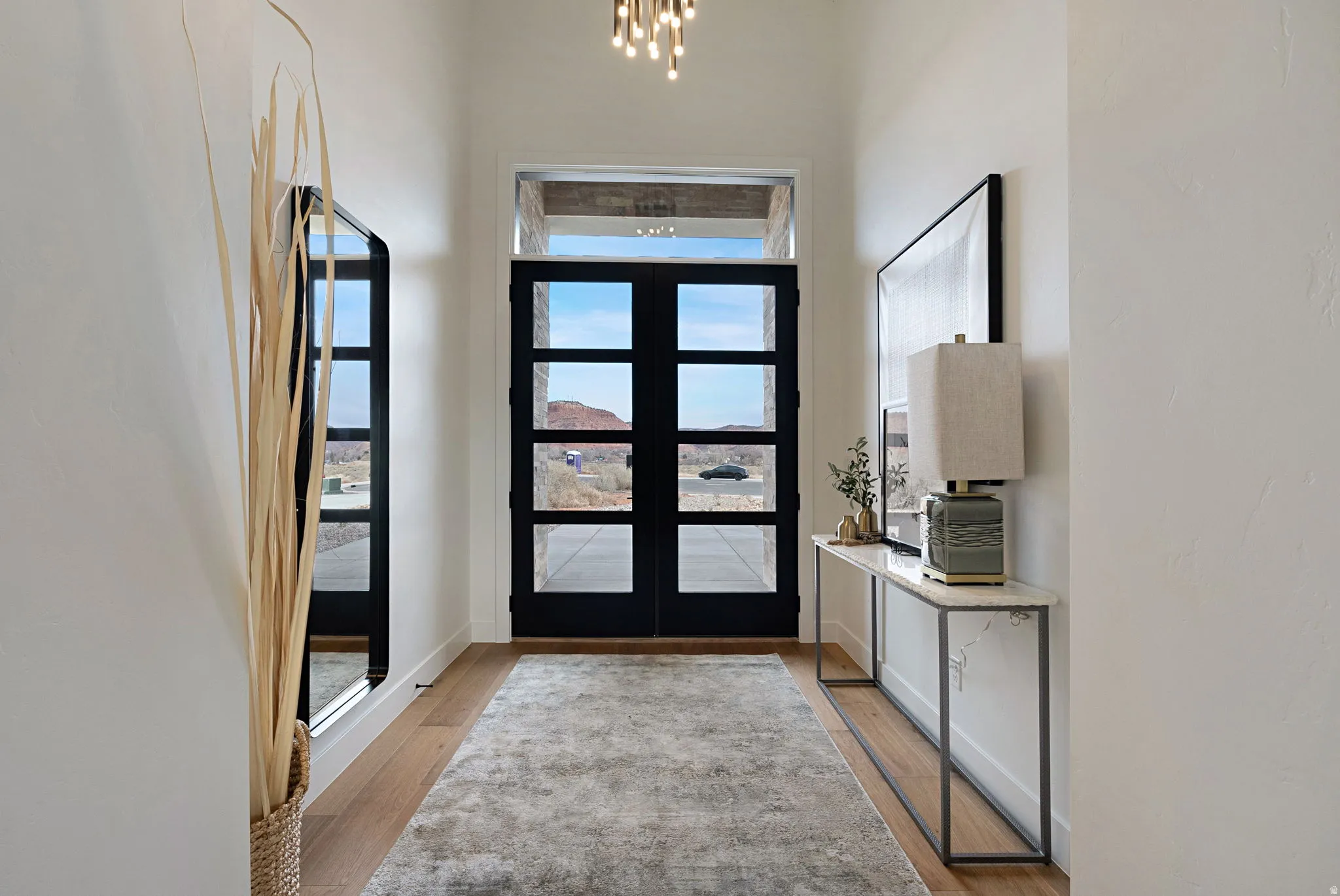 Entryway featuring a pair of four-pane black doors with transom window