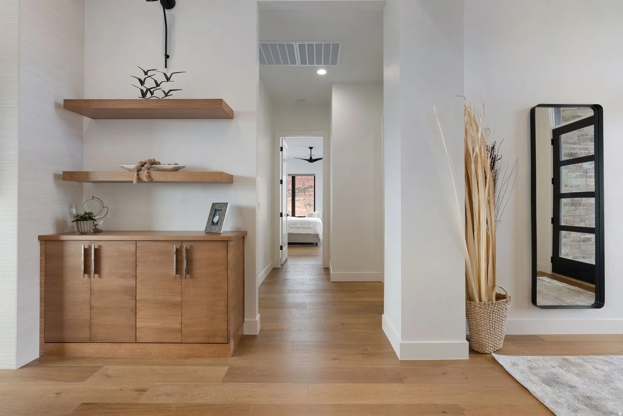 Entryway featuring wood-finish flooring, built-in cabinetry with modern hardware, and floating wood shelving