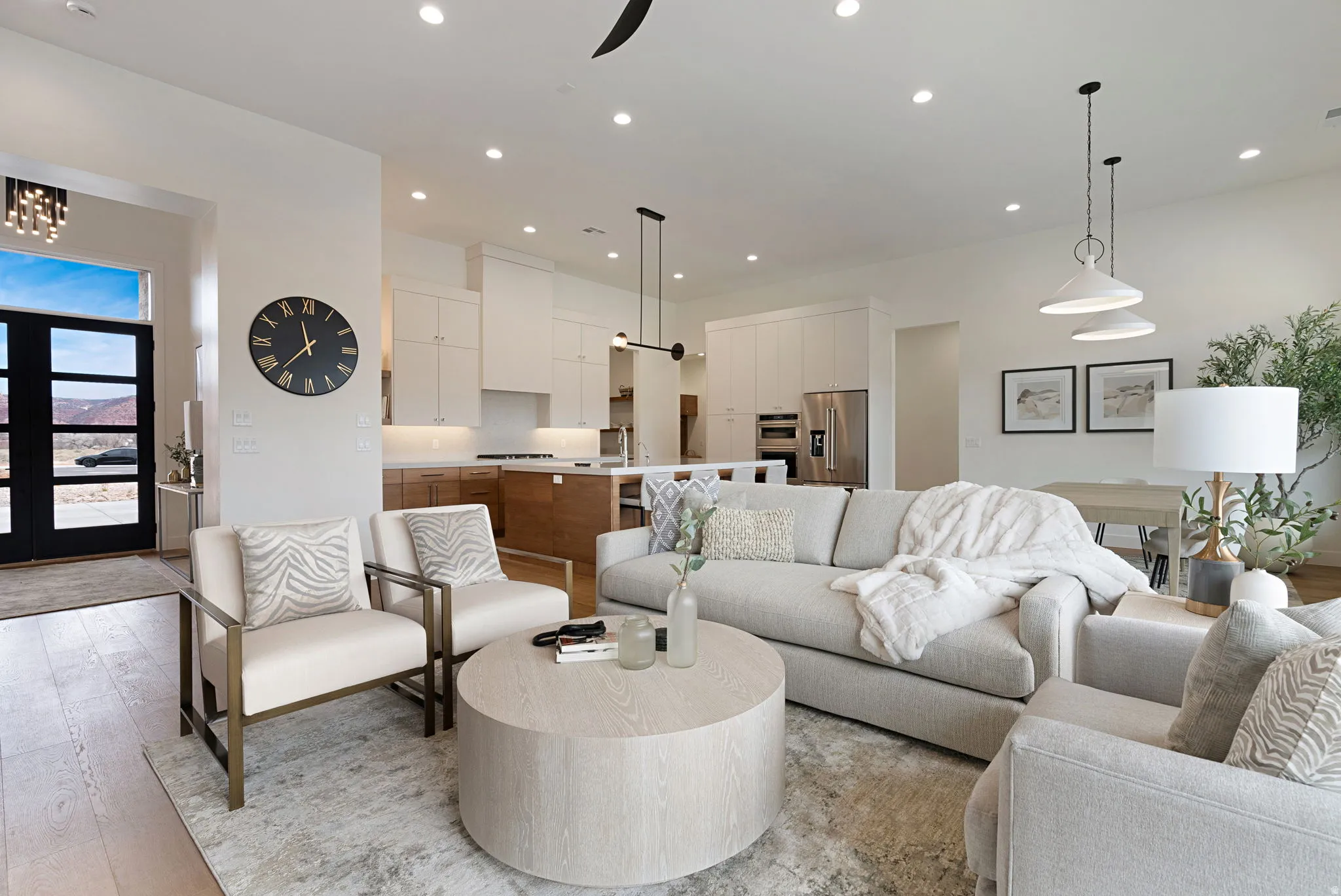 Open-concept living space featuring wood-finish flooring, recessed lighting, a modern kitchen with two-tone cabinetry, and a dining area with pendant lighting