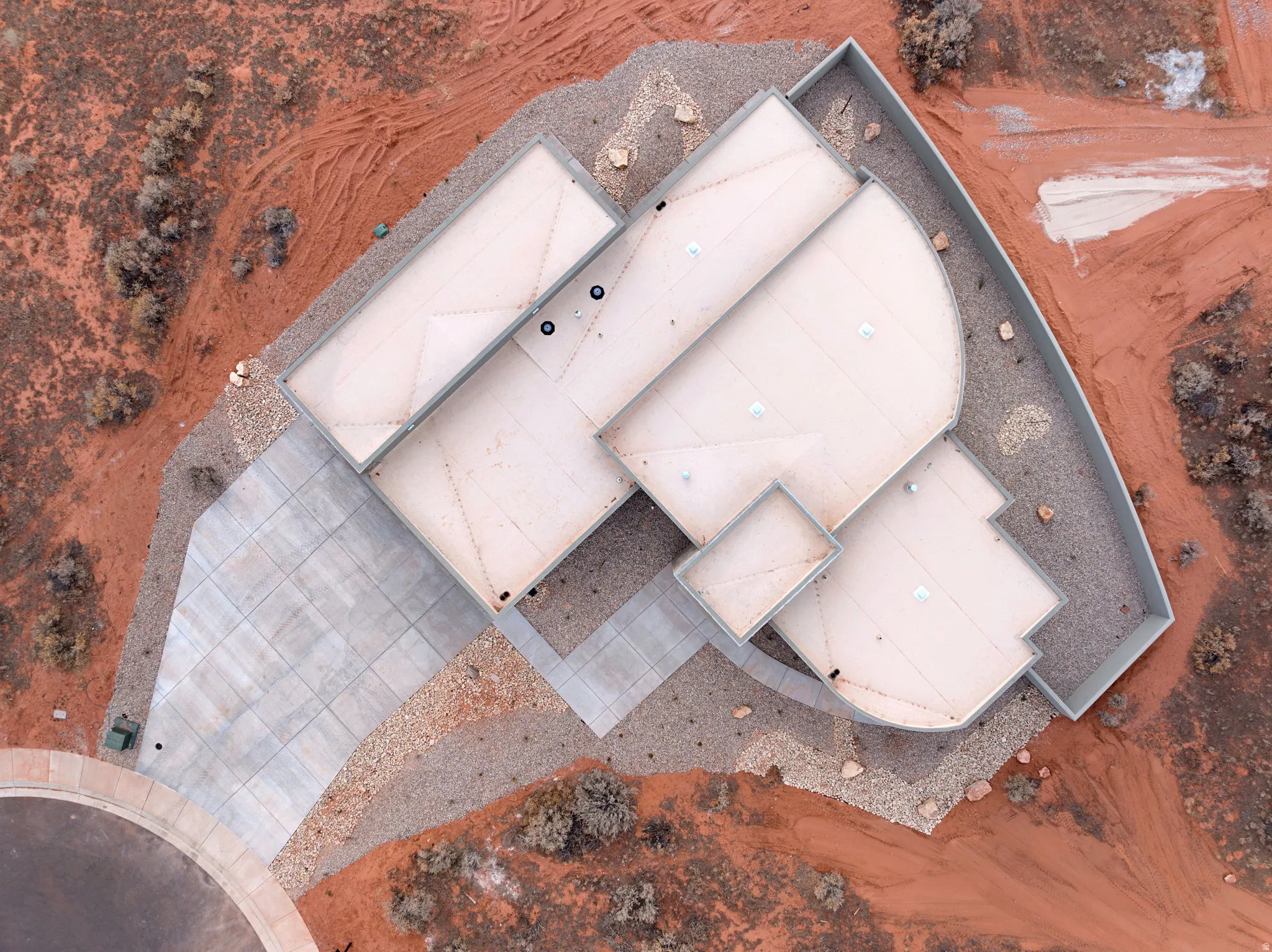 Contemporary architecture featuring a multi-level flat roof design, a curved concrete perimeter wall, and a segmented concrete driveway