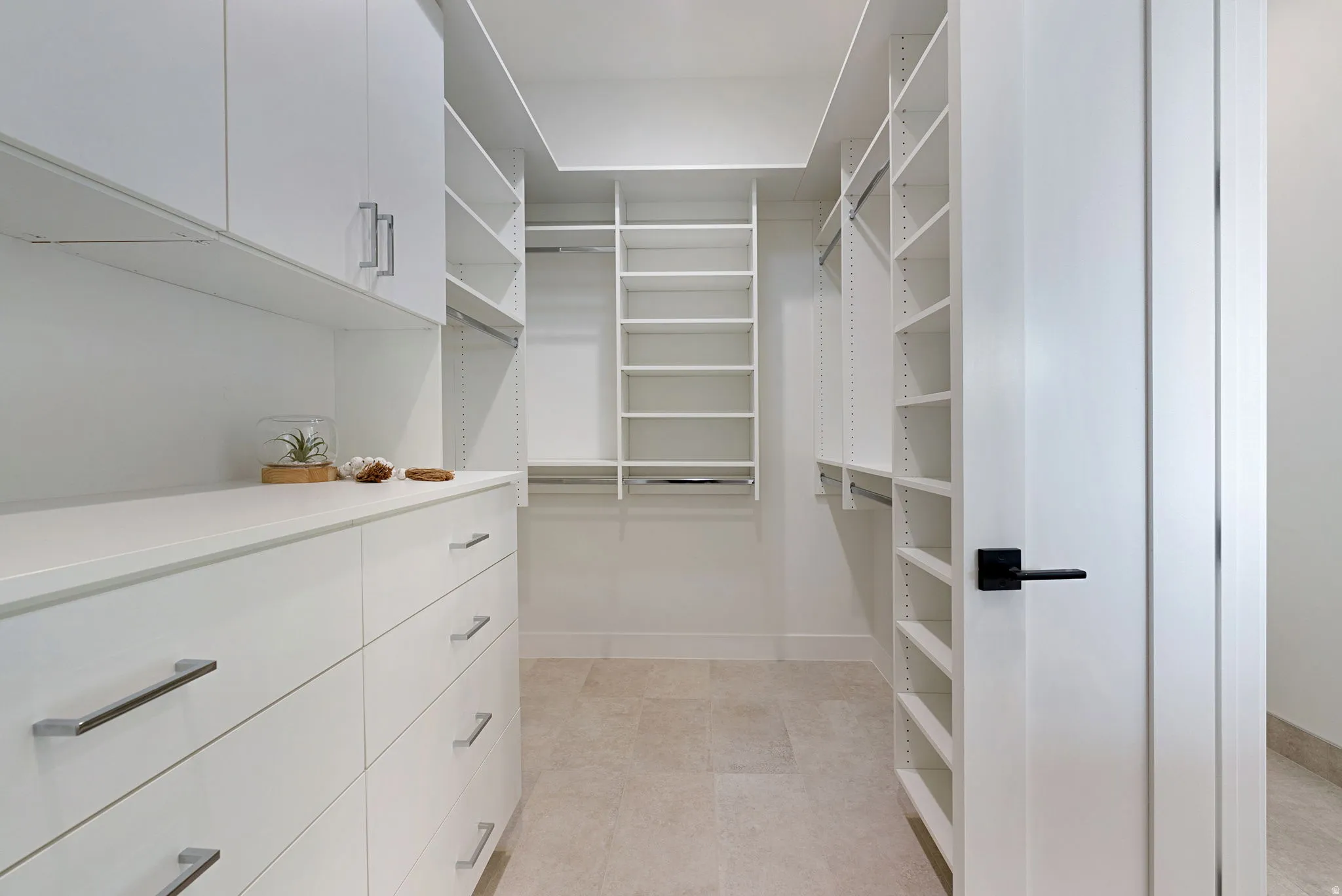 Custom closet system featuring extensive shelving, built-in drawer storage, hanging rods, and integrated cabinetry