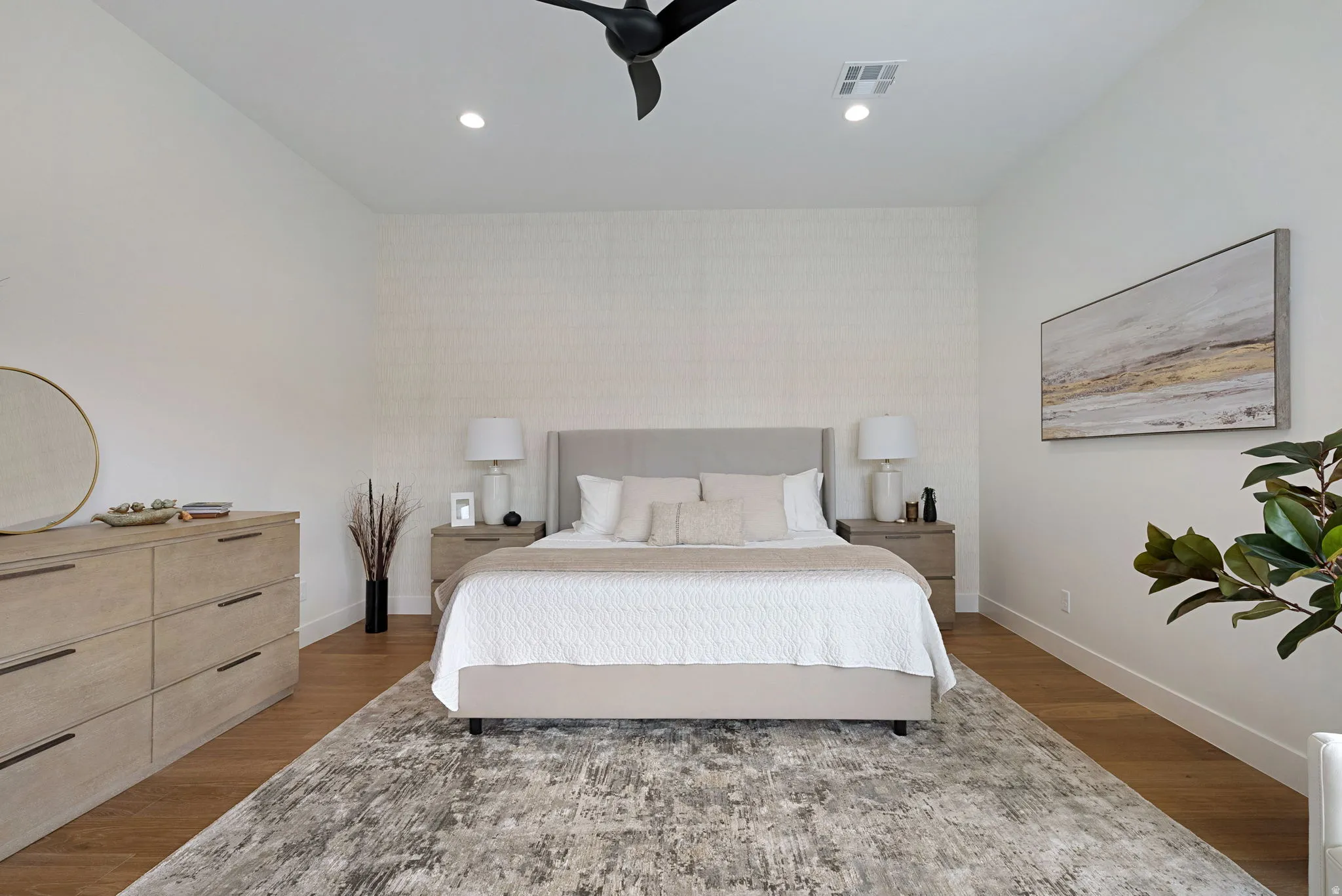 Recessed lighting illuminates the space featuring wood-finish flooring, a contemporary ceiling fan, and a textured accent wall