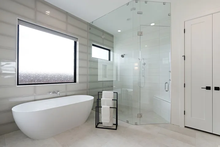 Contemporary bathroom featuring a freestanding soaking tub, a spacious glass-enclosed shower with a built-in bench, and large format wall tiling