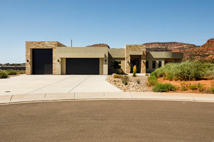 Modern stucco exterior with stone accents, integrated garage, and desert landscaping