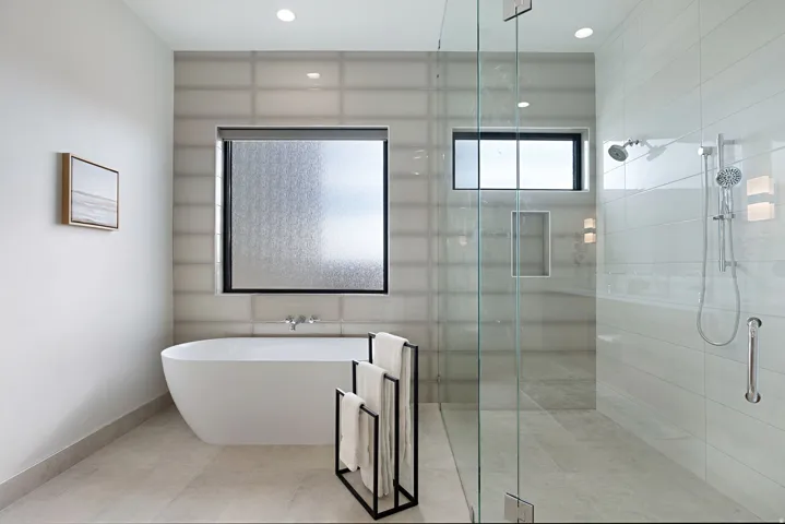Modern bathroom featuring a freestanding soaking tub, a spacious glass-enclosed shower with dual shower heads, and large format floor tiling