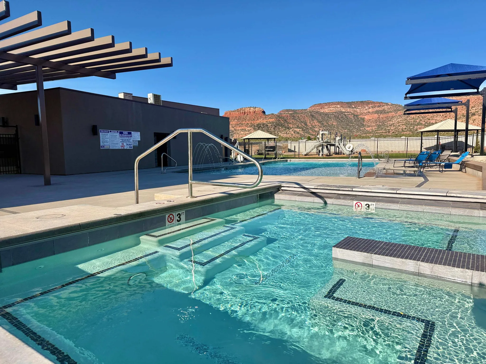 Resort-style pool with integrated steps and a splash pad feature