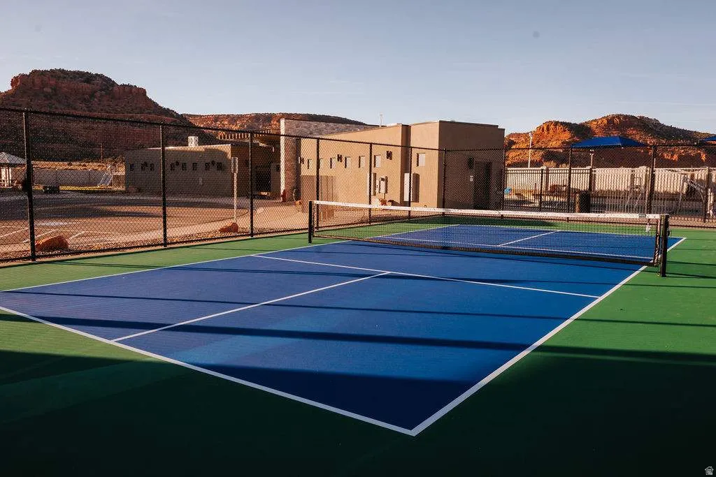 Outdoor pickleball court with blue and green surfacing, white line markings, and a perimeter fence