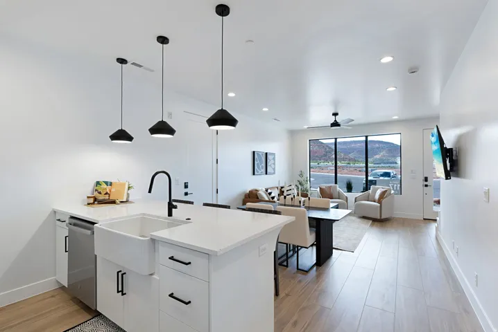 Open-concept living space featuring a modern kitchen island with a farmhouse sink, stainless steel dishwasher, and pendant lighting