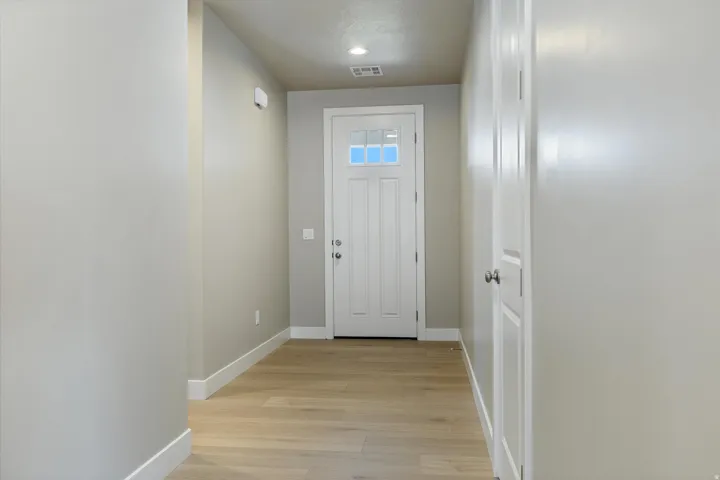 Entryway featuring a white paneled door with window accents, light wood-finish flooring, recessed lighting, and neutral wall tones