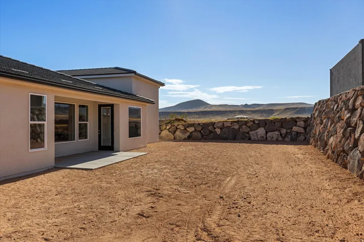 Newly constructed stucco exterior featuring a rear concrete patio and multiple windows
