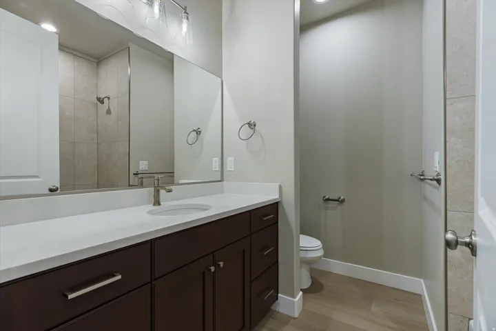 Modern bathroom featuring a dark wood-finish vanity with a white countertop and undermount sink