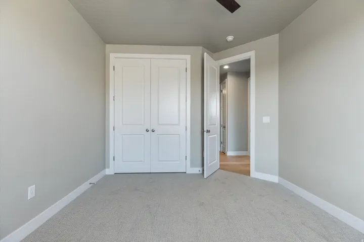 Neutral gray wall tones with white trim, light-toned carpet, and a white double-door closet