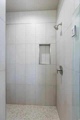 Walk-in shower featuring a chrome shower head and handle