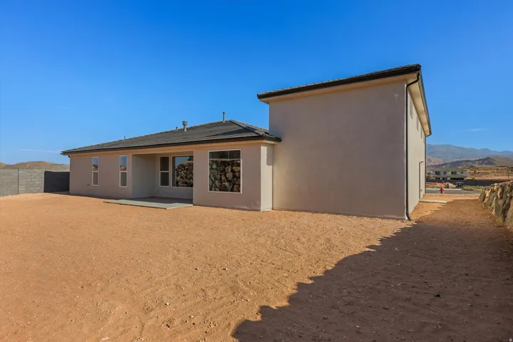 Contemporary stucco exterior with a covered patio, multiple windows, and a dark shingle roof