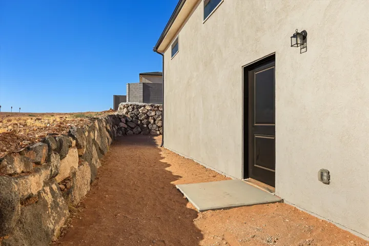 Stucco exterior featuring a dark paneled door, exterior wall lantern, and a concrete landing