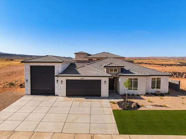 Contemporary stucco and stone exterior featuring a tile roof, a three-car garage with dark paneled doors, and a concrete driveway