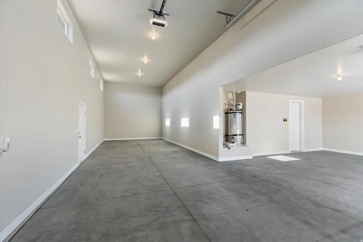 Spacious garage featuring a concrete floor, multiple windows, recessed lighting, a utility closet, and a white interior door