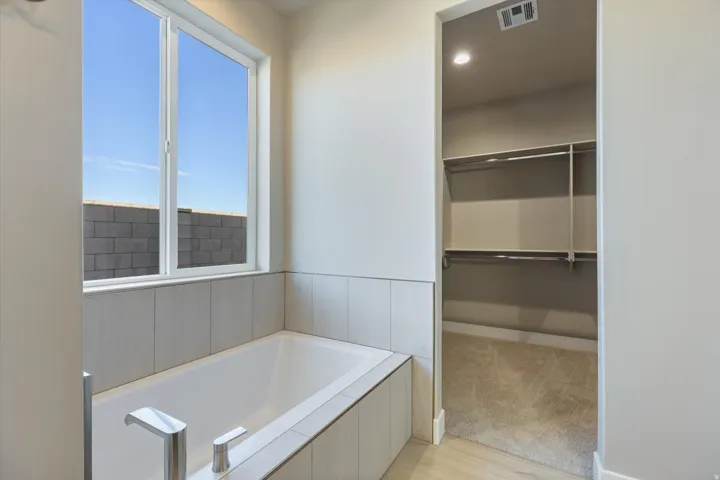 Soaking tub with sleek chrome fixtures and light-toned vertical tile surround