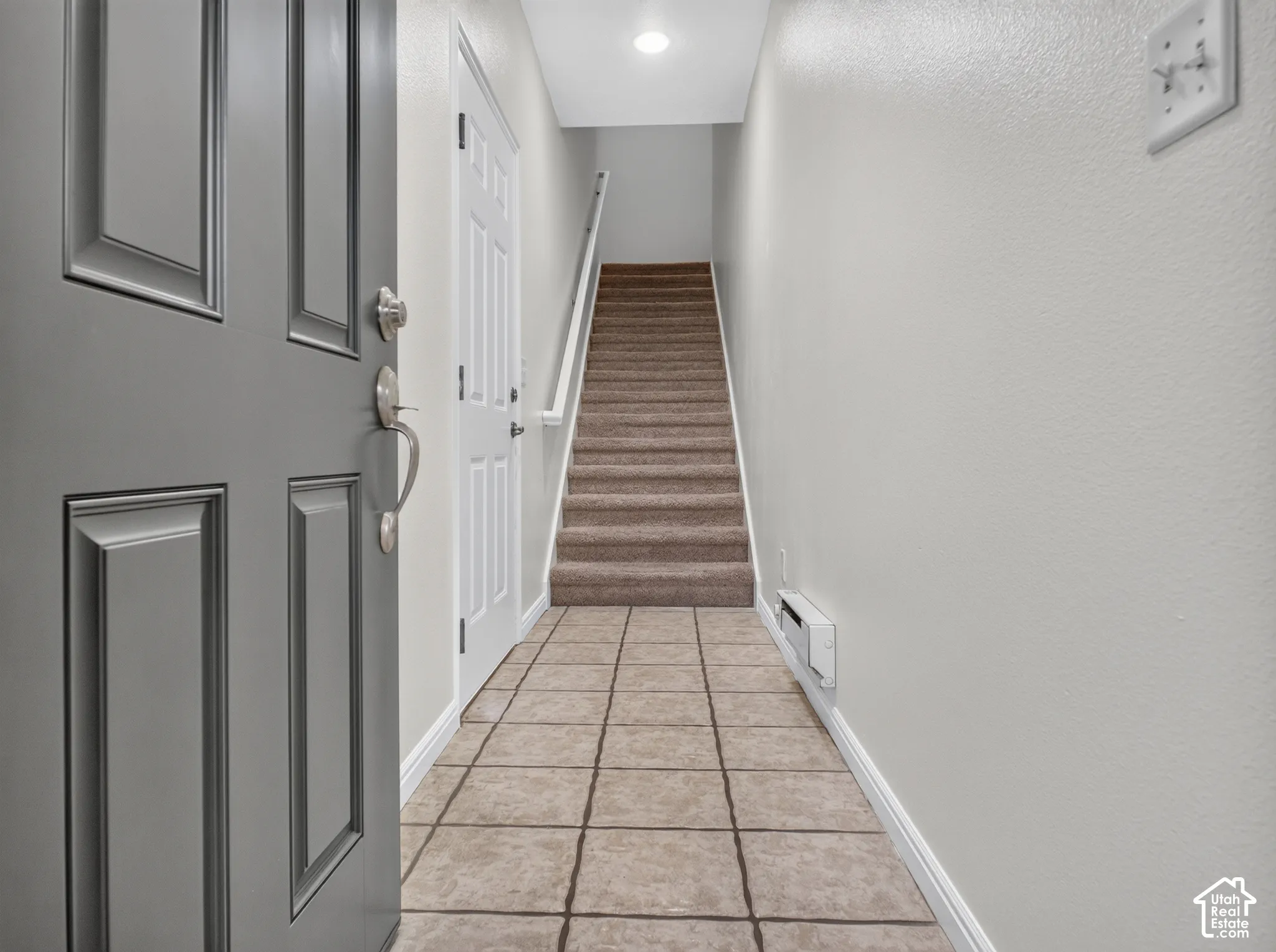 Tiled entry foyer with a paneled main door and neutral wall finishes