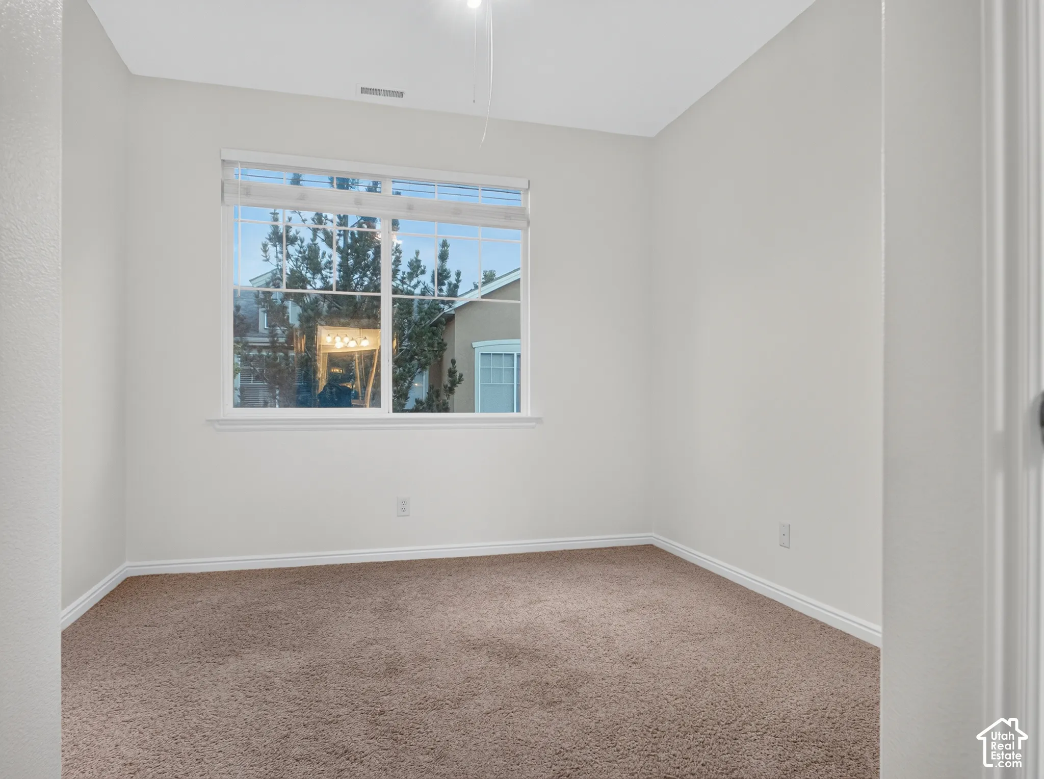 Neutral wall tones with a single window and warm-toned carpeting